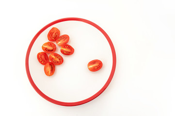 Seven and one red cherry tomato on white plate