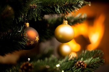 decorations on christmas tree and fire burning in fireplace in the background