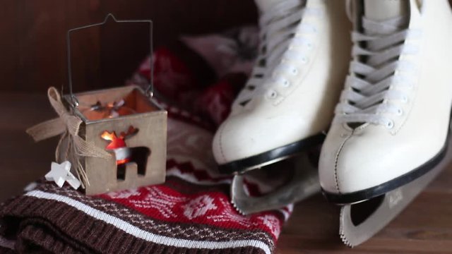 The candle burns in a wooden candlestick near the white female skates