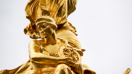 Statue of sitting gold female holding wheel