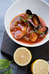 Close-up of tomato soup with vongole clams and mussels served in a white bowl, studio shot