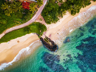 Aerial view of the tropical beach with palm trees on the shore and coral reef in the sea. Sri Lanka