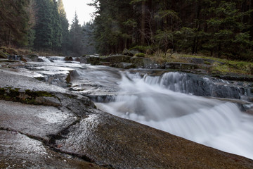 Fast-flowing water, picturesque blurred shapes of the water movement. Rocky shores. Beautiful Stream in the forest.