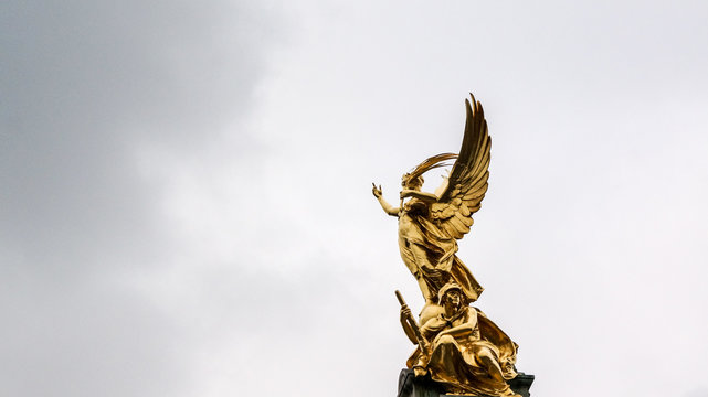 Statue of gold angel reaching toward the sky