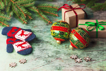 Christmas balls, decorations on a wooden background with spruce branches, children's mittens, wrapped gift.