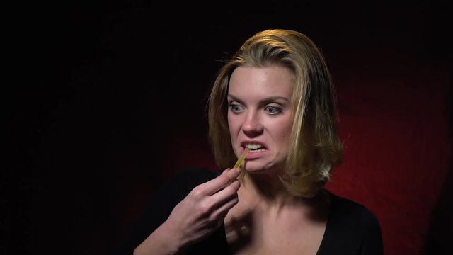 The blonde bites a jellyworm and shakes her hair, slow motion