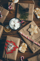 Cup of hot chocolate with marshmallows on wooden table with Christmas gifts