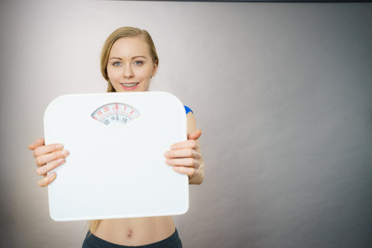 Teenage Woman Holding Bathroom Scale Machine