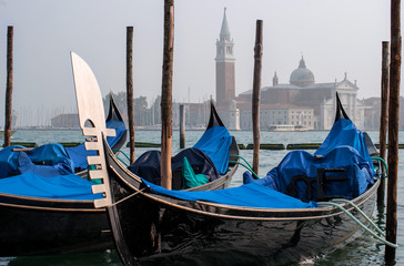 Fototapeta na wymiar Gondolas in Venice. The gondolas are moored at the mooring posts. Venice, Italy.