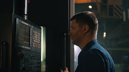 Worker using control panel on computer numerical control at production hall