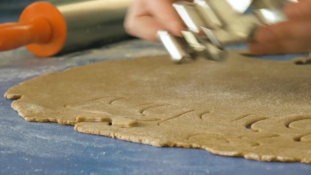 Woman cutting cookies with cutter, extreme closeup, dolly shot color graded