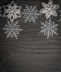 Snowflakes and stars over black wood with space for text