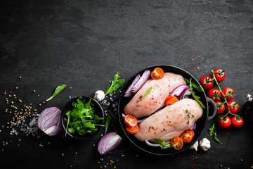 Fresh raw chicken meat, fillet marinated with spices, onion and tomatoes on black background. Top view - obrazy, fototapety, plakaty