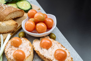 Slices of homemade bread with cream cheese and cherry tomatoes in bowl