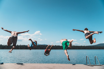 5 guys jumping in lake in a flying V. 