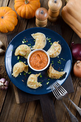 Typical Nepalese meal momo. Crescent shape steam dumplings with curry sauce served with pumpkins on rustic background