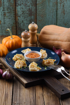 Vegetarian meal. Asian steam dumplings with curry sauce served with pumpkins and onion on rustic background