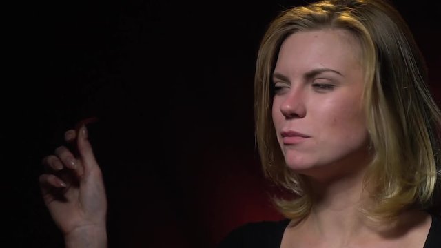 A beautiful blond woman in a black sweater tears off a piece of jelly worm