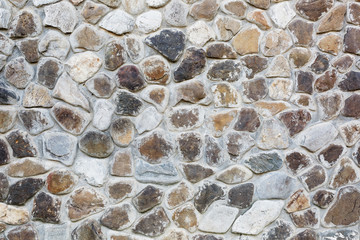 Large wall of natural stones of different size and colored gray texture on a summer day