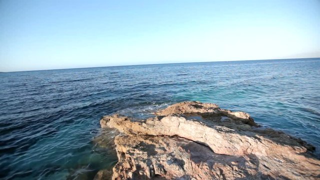 sea waves are beating against the stone shore. Greece. Wave splash beautiful turquoise blue water slow motion rocks sandy beach breeze summer holiday touristic seashore coast