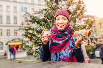 A woman with an appetite eats a traditional sweet pastry of Czech in Prague - a trdelnik on the background of a Christmas tree and a New Year's fair