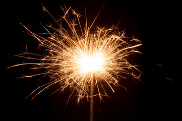 Burning New Year sparkler close up on black background
