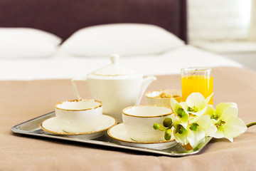 Fototapeta na wymiar Two white mugs on a tray white bed, breakfast concept