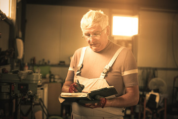 Senior Man writing in his planner book.