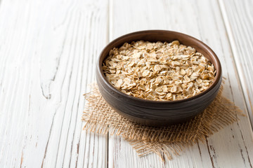 Oat flakes in ceramic bowl on white wooden table