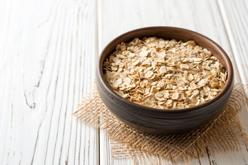 Oat flakes in ceramic bowl on white wooden table