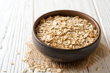 Oat flakes in ceramic bowl on white wooden table