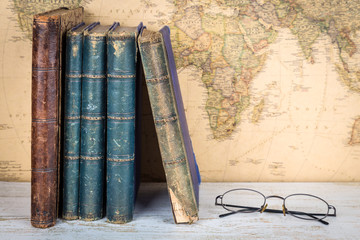 Travel and education concept. Old books and glasses, retro map background.