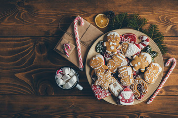 Plate with Christmas cookies on wooden table with cup of hot chocolate and gifts 