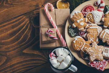 Plate with Christmas cookies on wooden table with cup of hot chocolate and gifts 