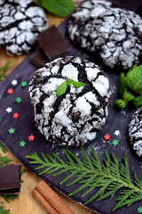 Chocolate crinkle cookies surrounded by Christmas attributes on a wooden board