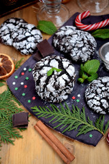 Chocolate crinkle cookies surrounded by Christmas attributes on a wooden board
