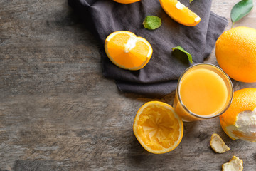 Glass of fresh juice and oranges on wooden background