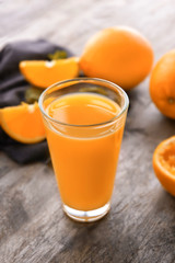 Glass of fresh orange juice on wooden background