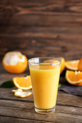 Glass of fresh orange juice on wooden background