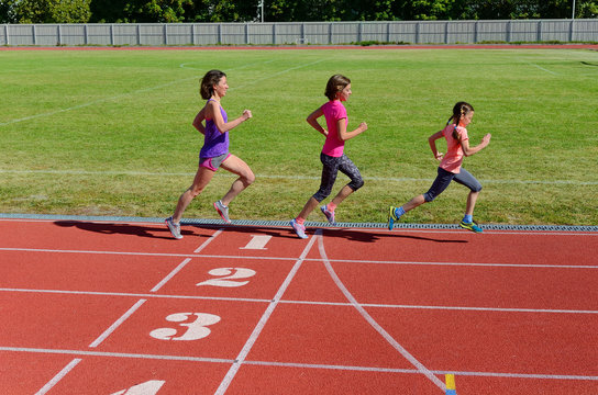 Family Sport And Fitness, Happy Mother And Kids Running On Stadium Track Outdoors, Children Healthy Active  Lifestyle Concept
