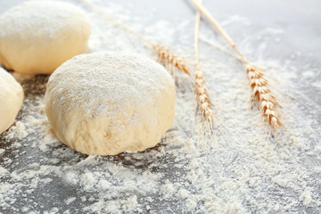 Raw dough balls with flour on table