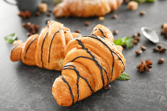 Delicious croissants with chocolate syrup on table