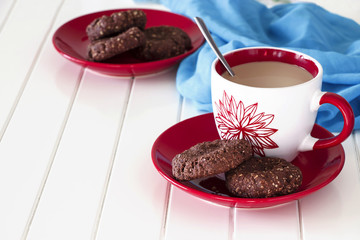 Chocolate oatmeal cookies and cup of milk tea. Blue and White wooden background. Selective focus.