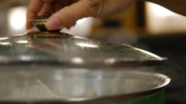 Closeup of lady hand opening steam sukiyaki pot lid