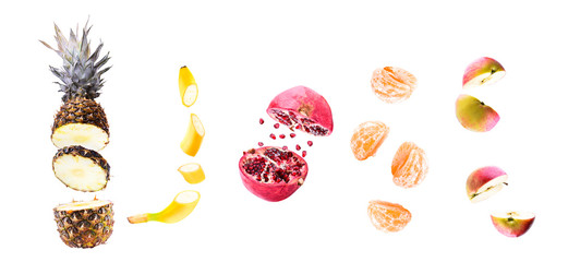 Fruit banner. Pieces of banana, pineapple, mandarin, pomegranate in flight on a white background, isolated. Cut sliced into pieces fruit mix flying in the air