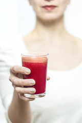 A glass of fresh juice a woman holds in her hand