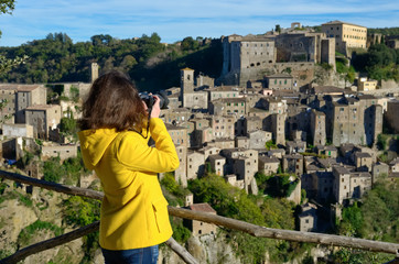 Woman tourist making photo of medieval tuff Sorano town in Italy
