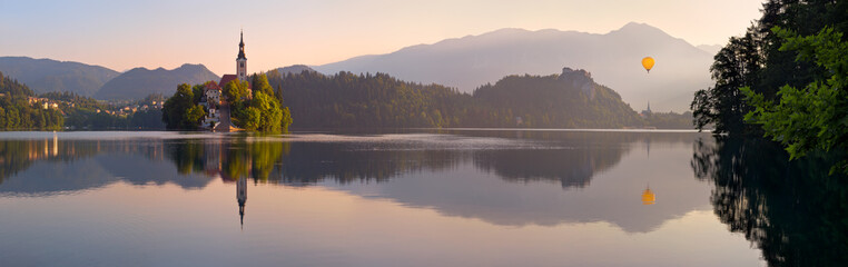 Church and Castle in lake Bled, Slovenia with Hot Air Balloon at Sunrise, scenic summer panorama