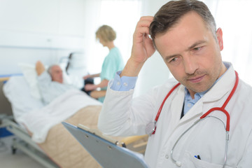 Fototapeta na wymiar frustrated mature doctor scratching his head in patients room