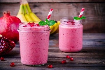 Pink pomegranate smoothie in a glass jar with mint and fresh seeds